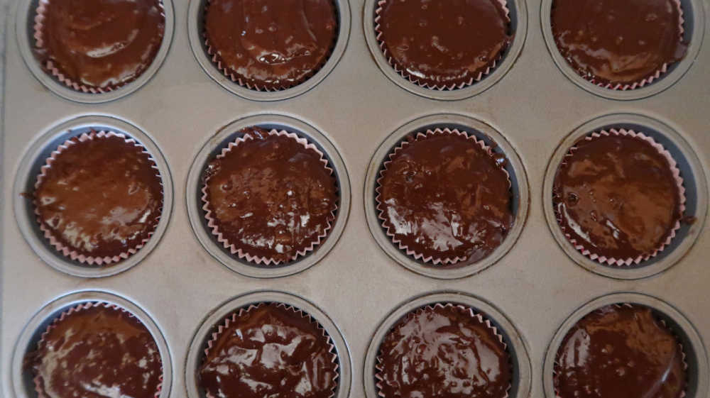 12 hole cupcake tin lined with cupcake liners and chocolate raspberry cupcake batter