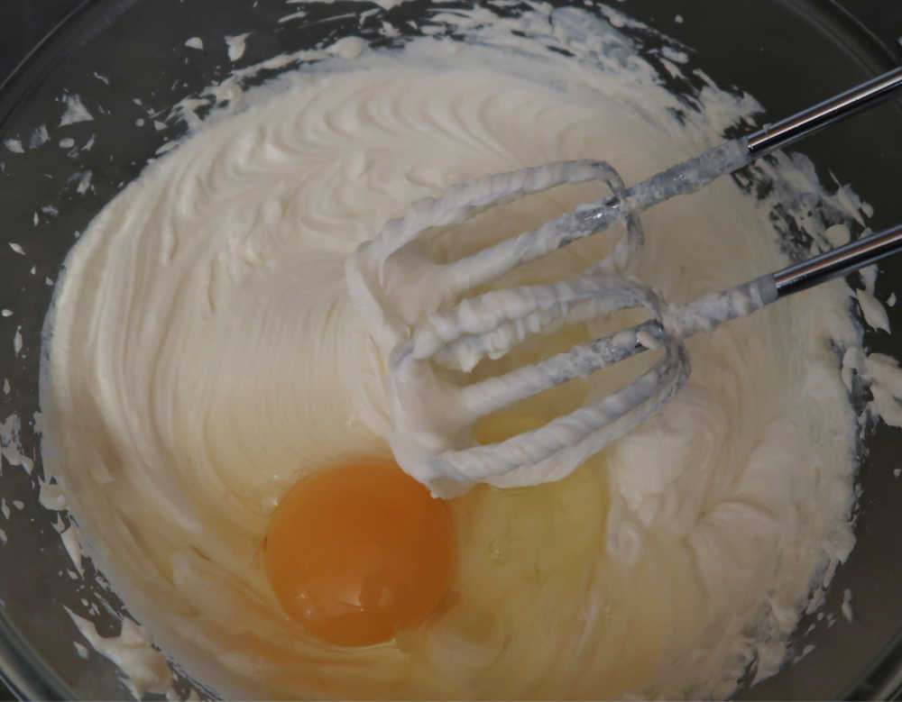 Adding eggs to the whisked cream cheese mixture